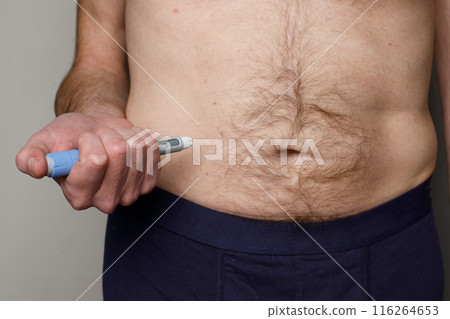 Man taking an insulin or semaglutide shot at home in his stomach. Man taking an insulin or semaglutide shot at home in his stomach. 116264653