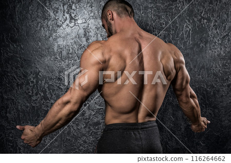 Man showing muscular back against conctete wall Man showing muscular back against conctete wall 116264662