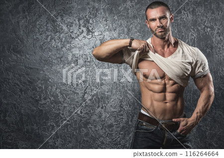 Man showing his body against concrete wall 116264664