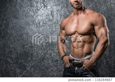 Man showing his body against concrete wall 116264667