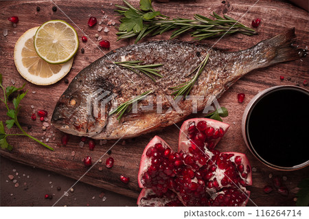 Fried dorado fish, with spices and herbs, on a wooden board, pomegranate sauce, close-up, no people, Fried dorado fish, with spices and herbs, on a wooden board, pomegranate sauce, close-up, no people, 116264714