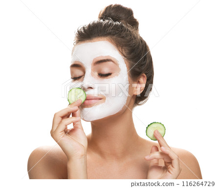 Woman with facial mask and cucumber slices in her hands Woman with facial mask and cucumber slices in her hands 116264729