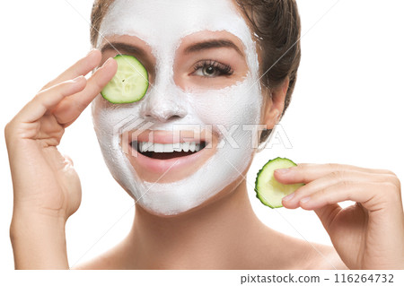 Woman with facial mask and cucumber slices in her hands Woman with facial mask and cucumber slices in her hands 116264732