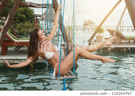 Beautiful woman on the swings which above a water 116264767