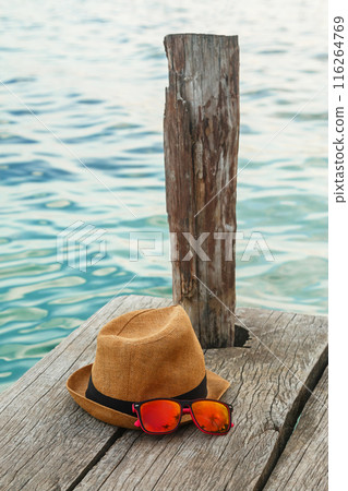 Straw hat and sunglasses on wooden pier 116264769
