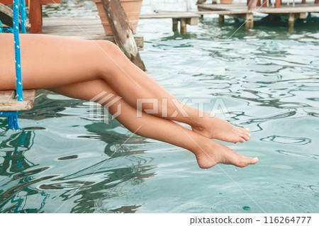 Closeup of Smooth female legs above blue water Closeup of Smooth female legs above blue water 116264777