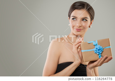 Glorious female model holding gift box in her hands on gray background with copy space.  116264778