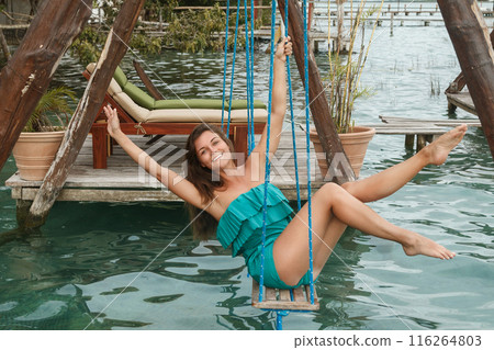 Beautiful woman on the swings which above a water Beautiful woman on the swings which above a water 116264803