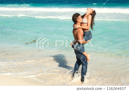 Beautiful couple wearing jeans on the tropical beach Beautiful couple wearing jeans on the tropical beach 116264837