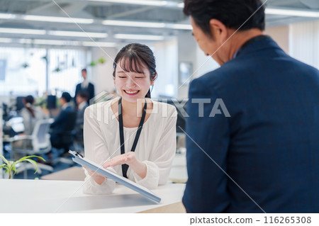 A female staff member assisting visitors at the counter 116265308