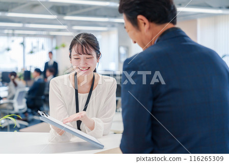 A female staff member assisting visitors at the counter 116265309