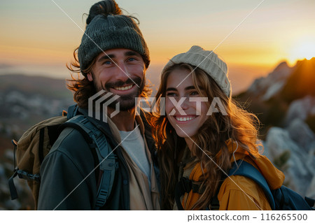 Caucasian couple hiking and wearing backpacks standing on mountain peak at sunset. Caucasian couple hiking and wearing backpacks standing on mountain peak at sunset. 116265500