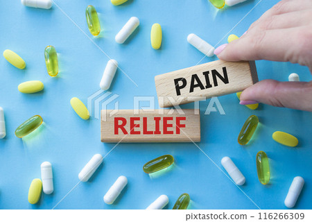 Pain Relief symbol. Concept word Pain Relief on wooden blocks. Beautiful blue background with pills. Doctor Hand. Medicine and Pain Relief concept. Copy space 116266309