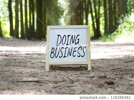 Doing Business symbol. Concept word Doing Business on white chalk background. Beautiful forest background. Business and Doing Business concept. Copy space 116266362