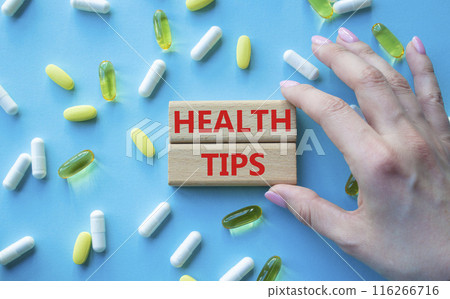 Health Tips symbol. Wooden blocks with words Health Tips. Beautiful blue background with pills. Doctor hand. Medicine and Health Tips concept. Copy space. 116266716