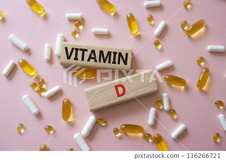Vitamin D symbol. Concept word Vitamin D on wooden blocks. Beautiful pink background with pills. Medicine and Vitamin D concept. Copy space 116266721