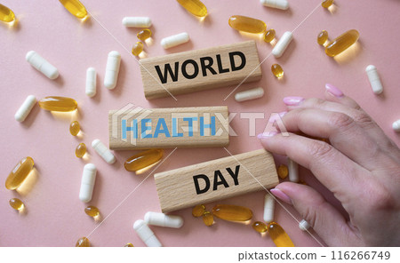 World Health Day symbol. Concept words World Health Day on wooden blocks. Beautiful pink background with pills. Doctor hand. Healthcare and World Health Day concept. Copy space. 116266749