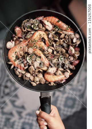 Hand holding skillet with seafood 116267008