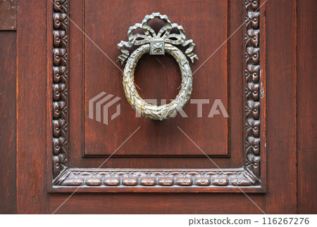 Leuven, Flanders, Belgium - Decorated antique door handle on a brown wooden door Leuven, Flanders, Belgium - Decorated antique door handle on a brown wooden door 116267276