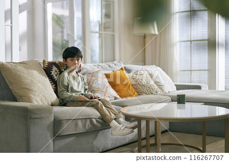 little asian boy sitting on family couch in living room at home 116267707