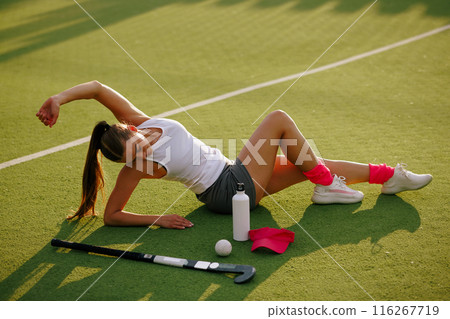 girl hockey player plays field hockey on a sunny day, hockey player drinks water during a break in the match, active sport for girls girl hockey player plays field hockey on a sunny day, hockey player drinks water during a break in the match, active sport for girls 116267719