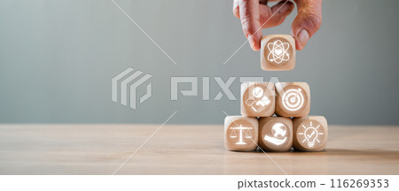Hand stacking wooden blocks with icons symbolizing core values such as innovation, balance, and growth, illustrating foundational principles in business and life. 116269353
