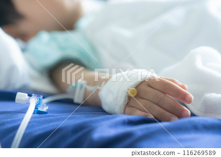 Asian todler in hospital with intravenous saline. Sick children, infected with the virus, are lying and being treated in beds in hospitals. 116269589