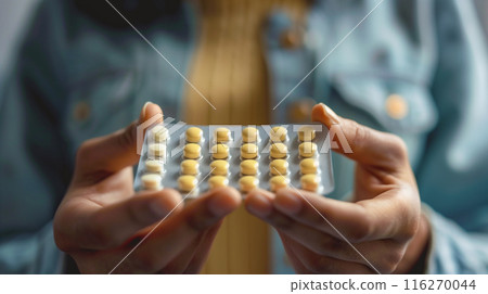 Woman's hand holding a pill. Image of a woman taking contraceptive pills 116270044