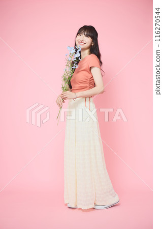 Woman holding delphinium on a pink background 116270544