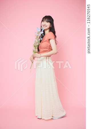 Woman holding delphinium on a pink background Woman holding delphinium on a pink background 116270545