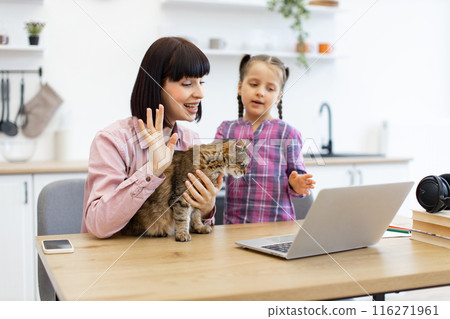 Mother and daughter having video call with cat on desk Mother and daughter having video call with cat on desk 116271961