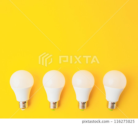 Four white light bulbs are arranged on a yellow background Four white light bulbs are arranged on a yellow background 116273825