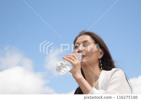 一位微笑的老年婦女透過保持水分來預防中暑 一位微笑的老年婦女透過保持水分來預防中暑 116275180