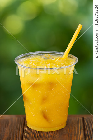 disposable plastic glass of cold orange juice with ice and straw 116275224