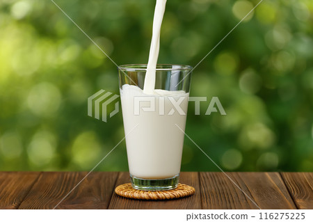 milk pouring into glass on wooden table 116275225