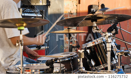 A black drum set, complete with drumsticks, cymbals, and microphones, is set up for a recording session or live performance, highlighting the various components of the kit. 116275732