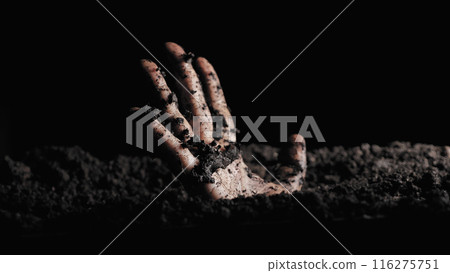 A solitary hand emerges from the soil, gripping the earth, symbolizing themes of struggle, desperation, and the powerful will to break free or resurrect. 116275751