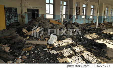 An abandoned, dilapidated building littered with piles of rubbish and bags of waste. Sunlight streams through the broken windows, illuminating the disorder and decay inside. An abandoned, dilapidated building littered with piles of rubbish and bags of waste. Sunlight streams through the broken windows, illuminating the disorder and decay inside. 116275774