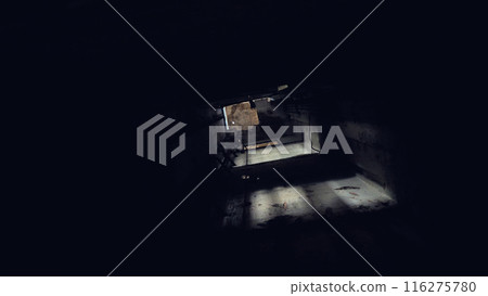 A dark tunnel of a lift shaft with a small opening at the end through which light enters. The atmosphere is eerie and mysterious, with shadows and dim lighting creating a sense of depth and intrigue. 116275780