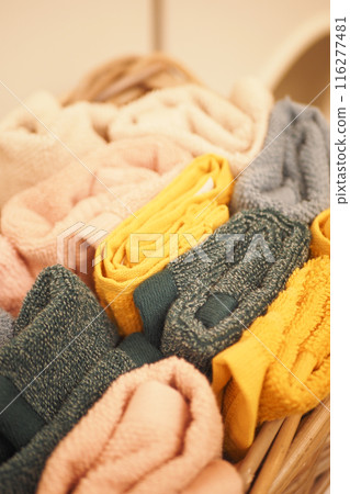 A storage basket made of wood filled with an assortment of towels 116277481