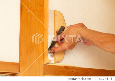 A craftsman replacing wallpaper on a house 116278181