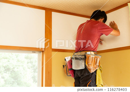 A craftsman replacing wallpaper on a house A craftsman replacing wallpaper on a house 116278403