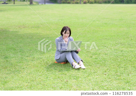 一位女士在草坪上操作電腦 一位女士在草坪上操作電腦 116278535