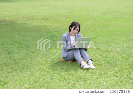 一位女士在草坪上操作電腦 一位女士在草坪上操作電腦 116278536