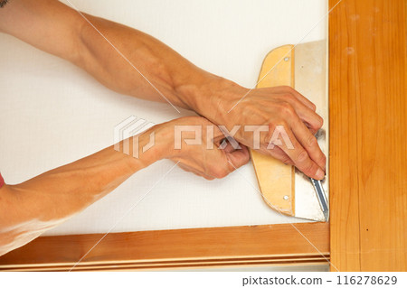 A craftsman replacing wallpaper on a house 116278629