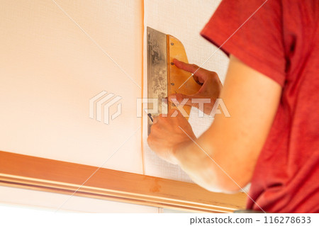 A craftsman replacing wallpaper on a house 116278633