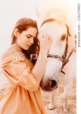 A white horse and a woman in a dress stand on a beach, with the A white horse and a woman in a dress stand on a beach, with the 116279463