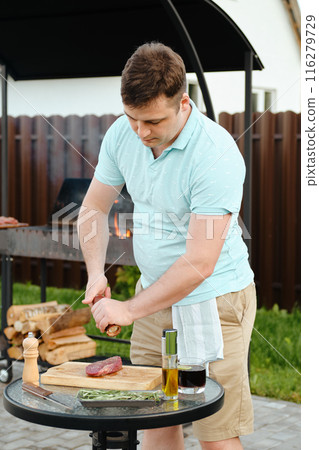 Man cooking steak for outdoor barbecue 116279729