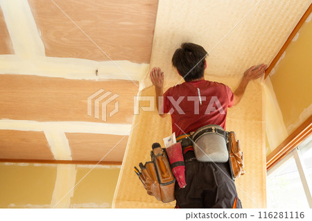 A craftsman replacing wallpaper on a house 116281116