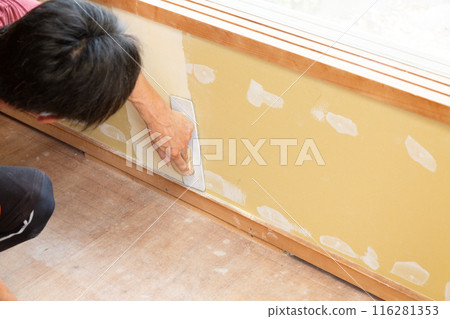 A craftsman replacing wallpaper on a house 116281353